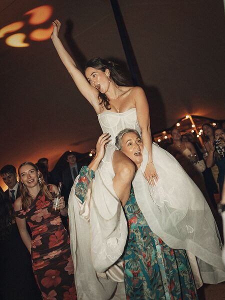 La mariée portée sur les épaules d'une invitée, au milieu de la fête