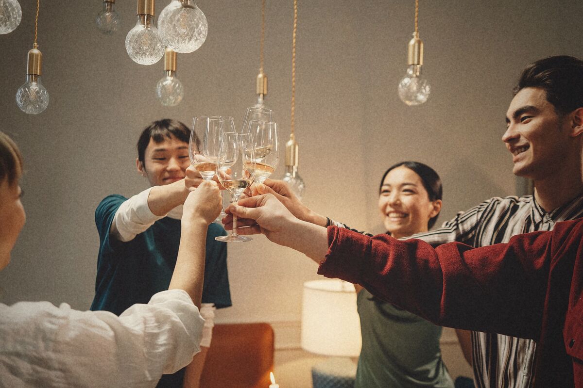 Des verres qui trinquent au-dessus d'une table, sous des ampoules